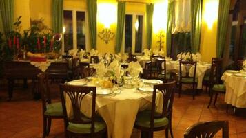 A restaurant with multiple tables set for dining, featuring green chairs and white tablecloths.