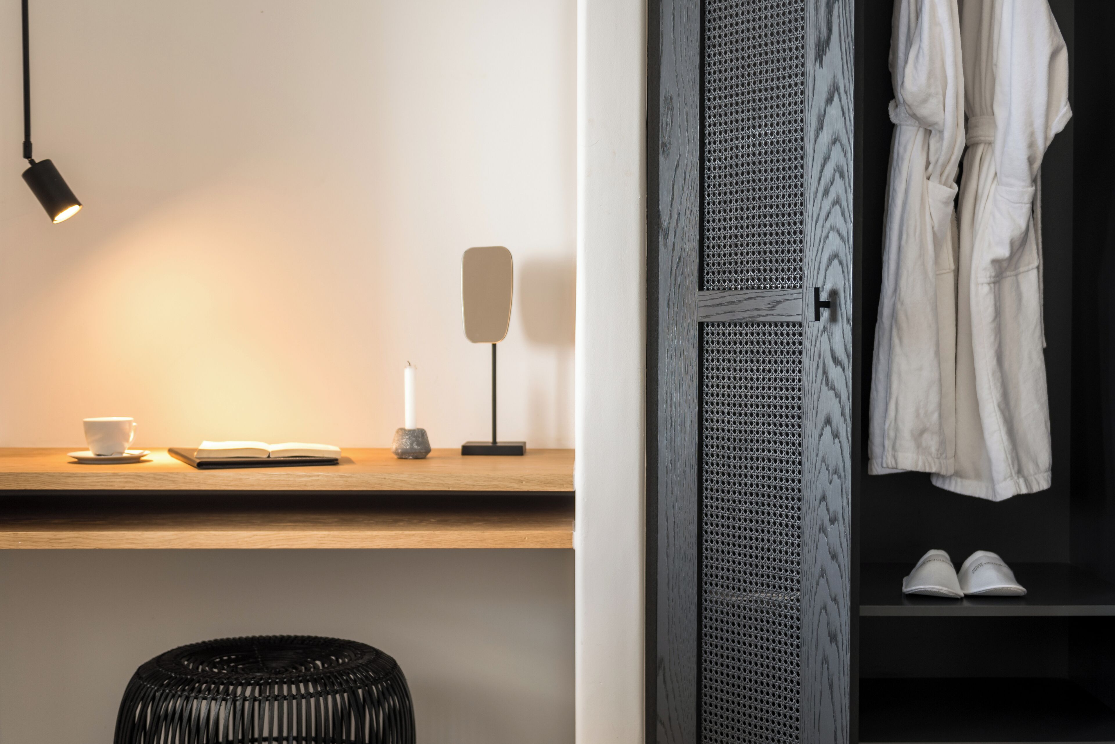 Een moderne kamer met een houten bureau, een leeslamp, een kopje en een paar schoenen op een plank.