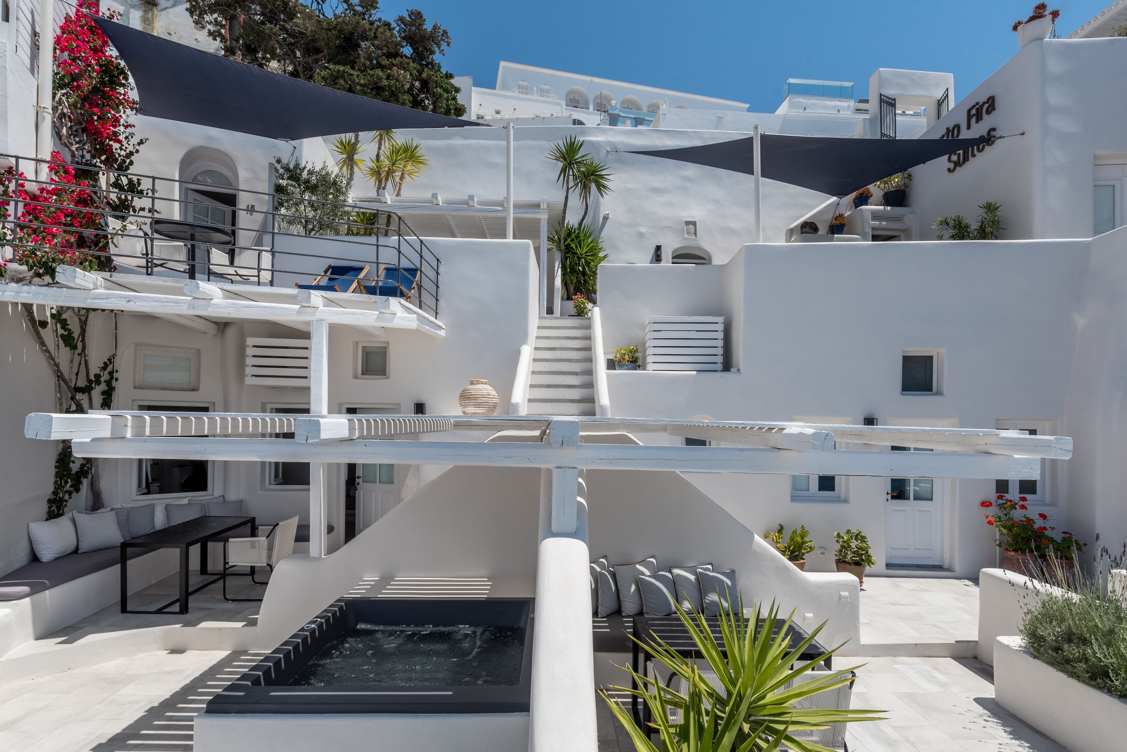 Une terrasse sur le toit avec des sièges extérieurs, un jacuzzi et un escalier menant aux niveaux supérieurs.