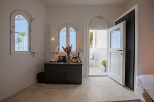 Un interior moderno con una consola oscura, un florero con flores y vistas a través de un ventanal arqueado.