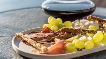 Una tabla con quesos variados, carnes y uvas sobre una mesa.