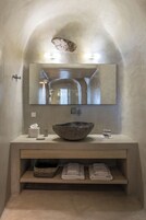 Un bagno moderno con un grande specchio, un lavabo in pietra e un mobile contenitore in legno.