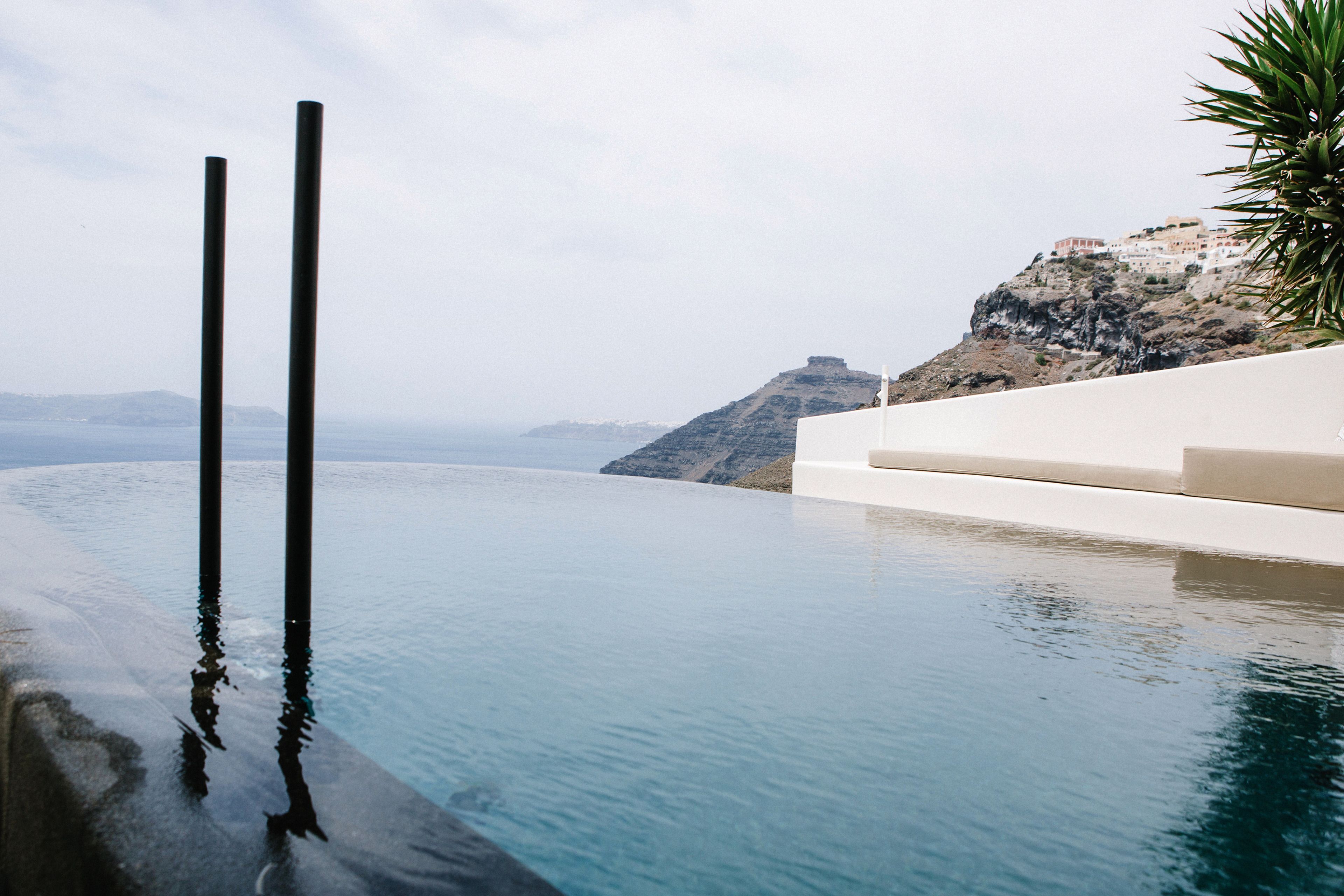 A infinity pool with a view of a mountainous coastline.