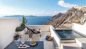 A terrace with a view of the sea, a hot tub, and outdoor seating. - Porto Fira Suites (Santorini)