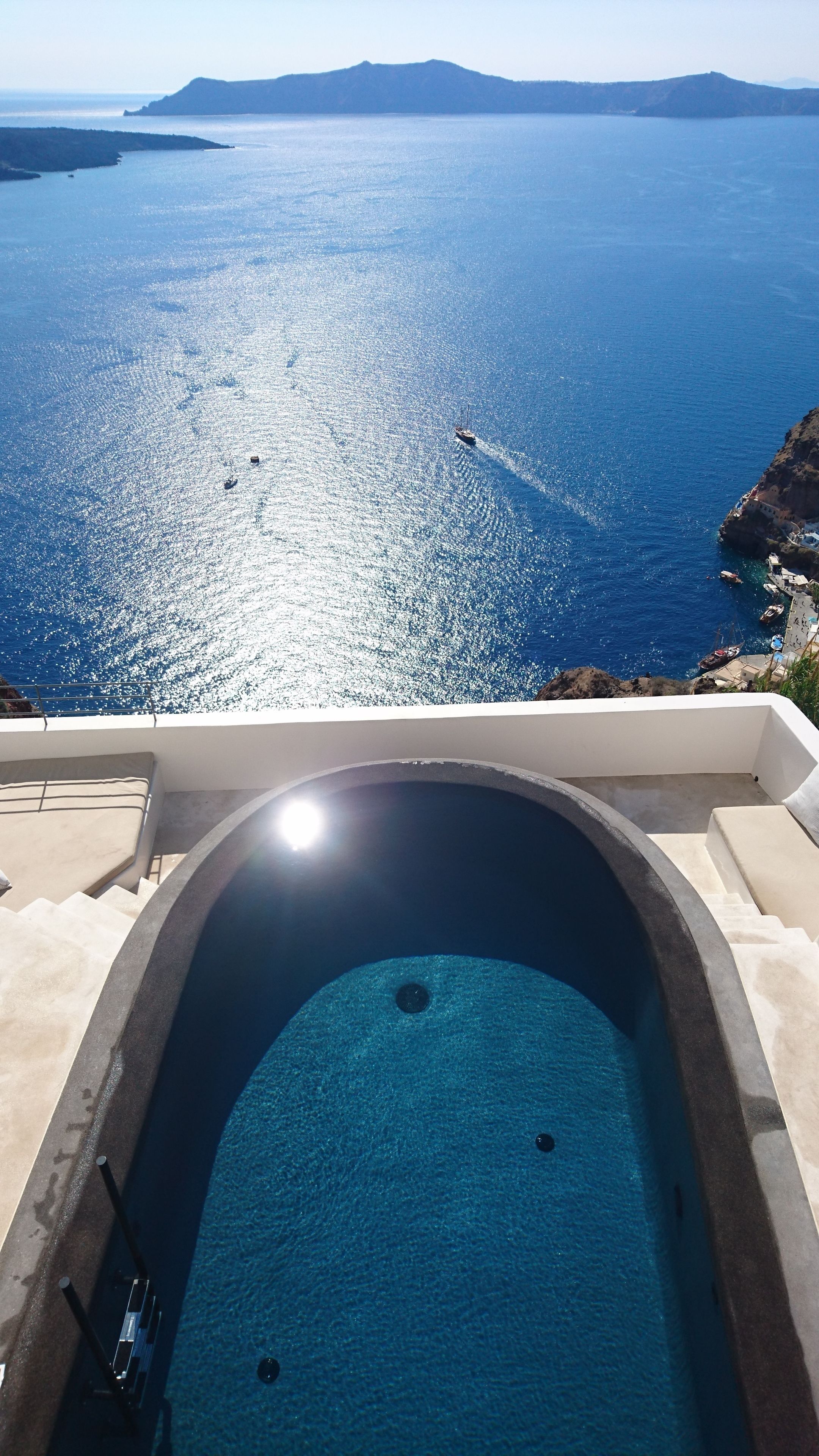 A pool with a clear view of the sea and distant hills.
