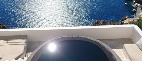 A pool with a clear view of the sea and distant hills.