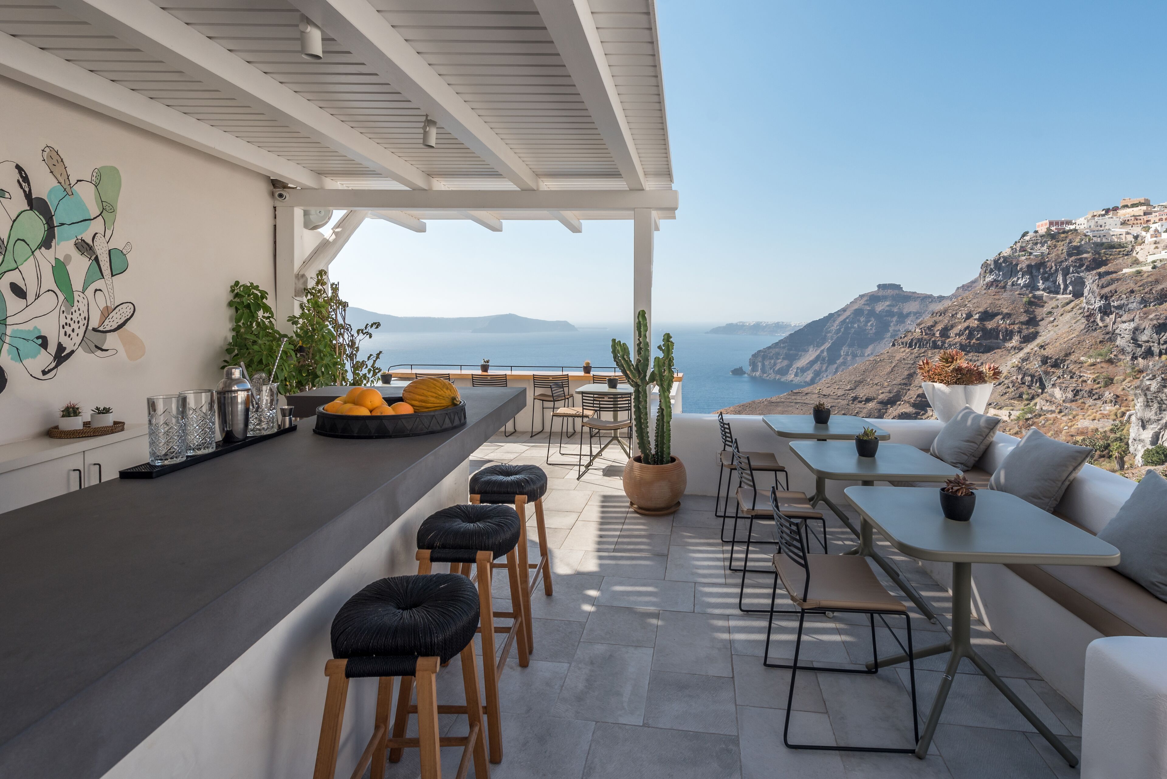 A modern outdoor dining area with a view of the sea and mountains.