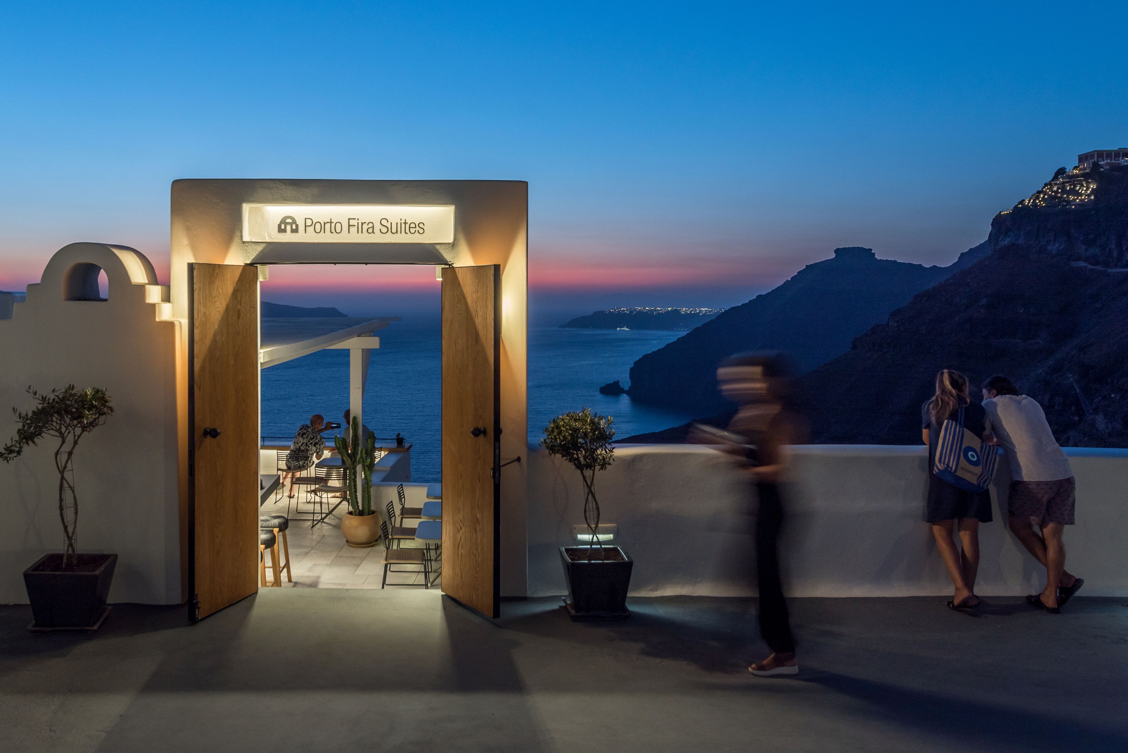 An entrance to Porto Fira Suites with a view of the sea and mountains.