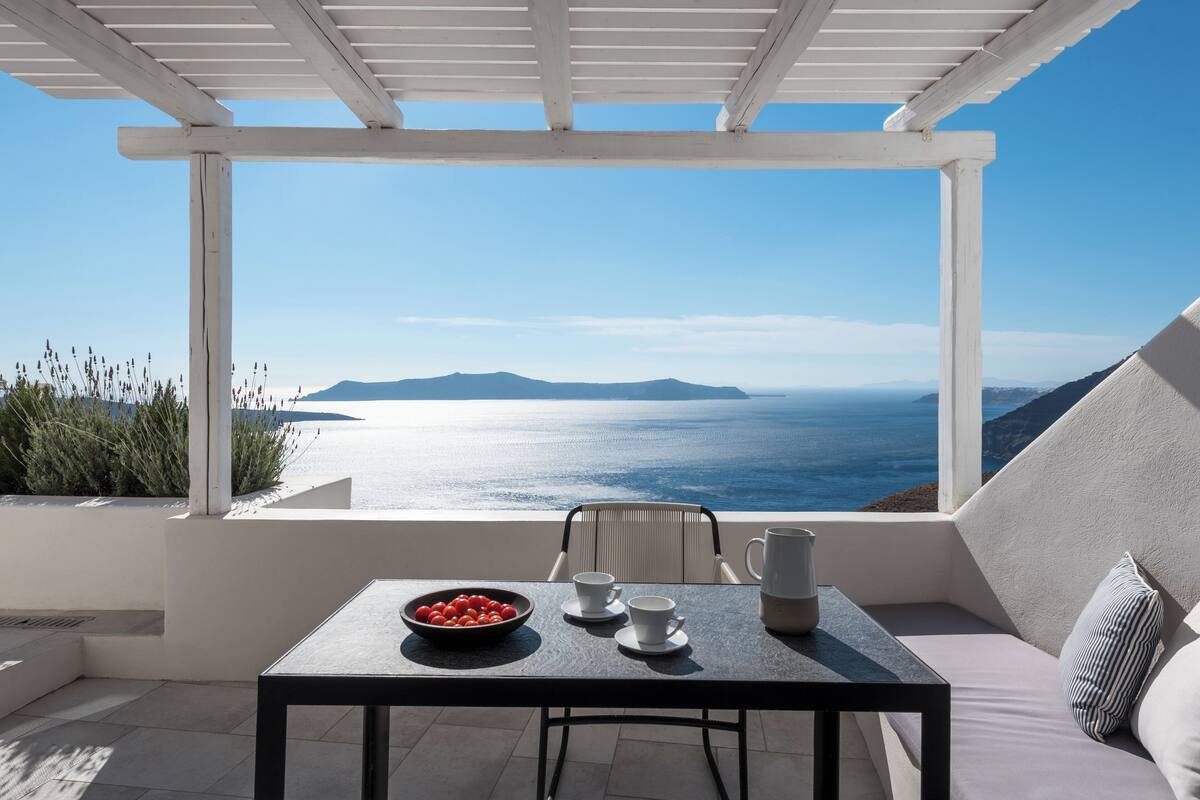 A balcony with a table, chairs, and a bowl of fruit.