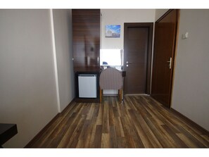 Ein Flur mit Holzboden, einem kleinen Kühlschrank, einem Stuhl und einer Tür.