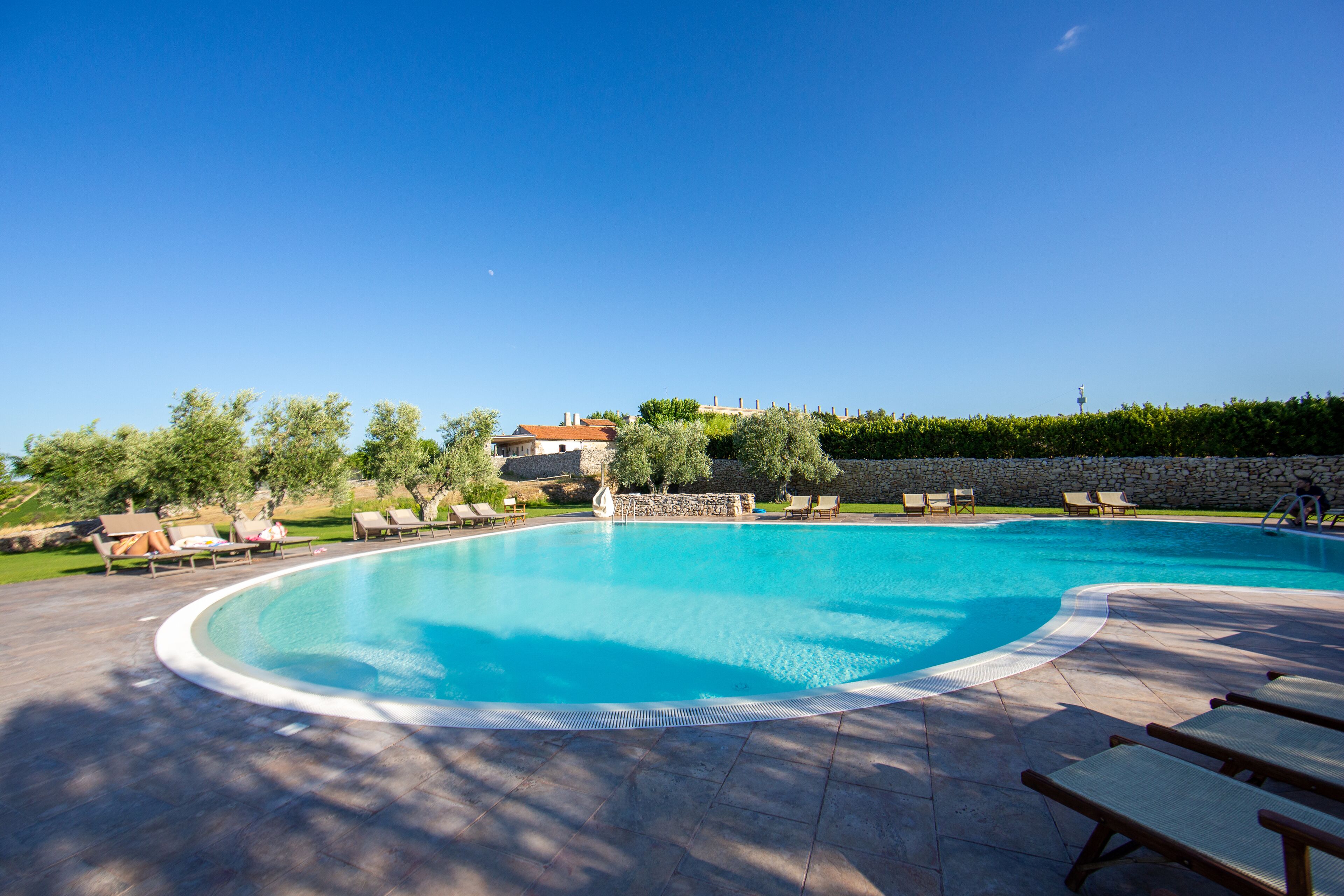 Una piscina al aire libre, sillones reclinables de piscina