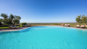 Ein klares, blaues Schwimmbecken mit Liegestühlen und Blick auf den Horizont.