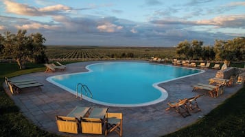 Una piscina al aire libre, sillones reclinables de piscina