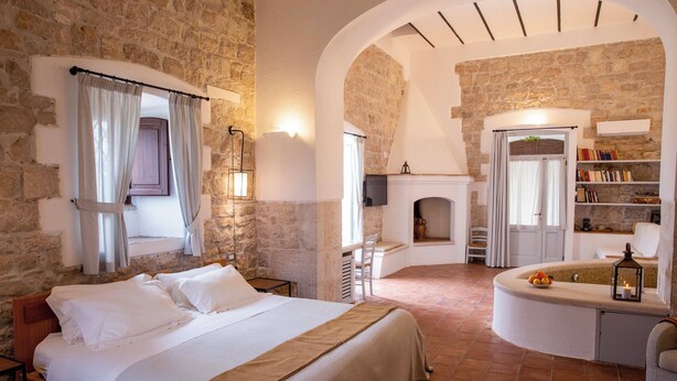 Ein Schlafzimmer mit einem großen Bett, einem Kamin und einer Steinwand.