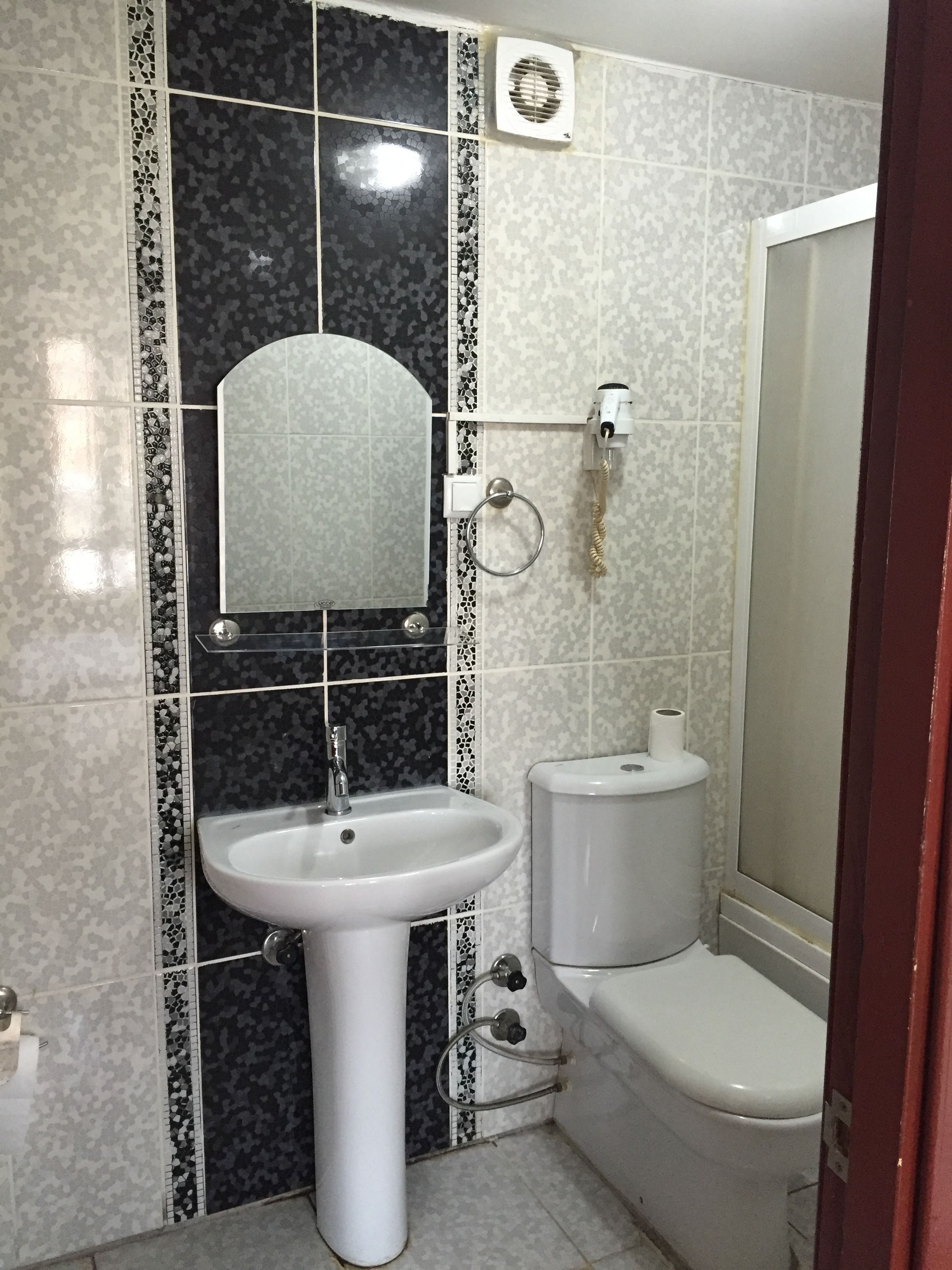 Un baño con lavamanos blanco, inodoro y espejo.