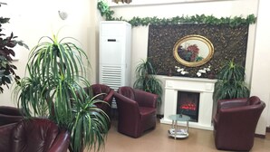 Una sala de estar con sofás de cuero, chimenea y plantas en macetas.
