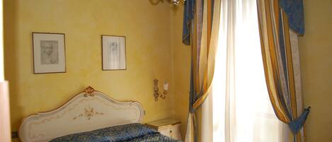 A bedroom with a bed, a chandelier, and curtains.