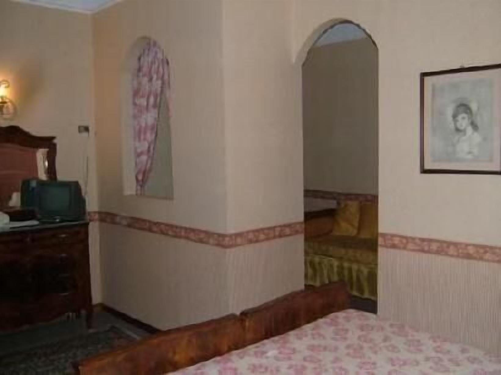 A hotel room with a bed, a dresser, a television, and a framed picture on the wall.