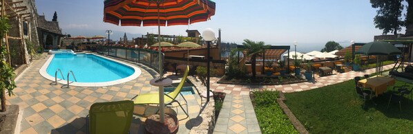 A pool area with a checkered floor, lounge chairs, and umbrellas. - Garda Sol Apart-hotel Beauty & SPA (Toscolano Maderno)