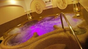 A hot tub with a purple light, a metal ladder, and a tiled wall with a statue. - Garda Sol Apart-hotel Beauty & SPA (Toscolano Maderno)