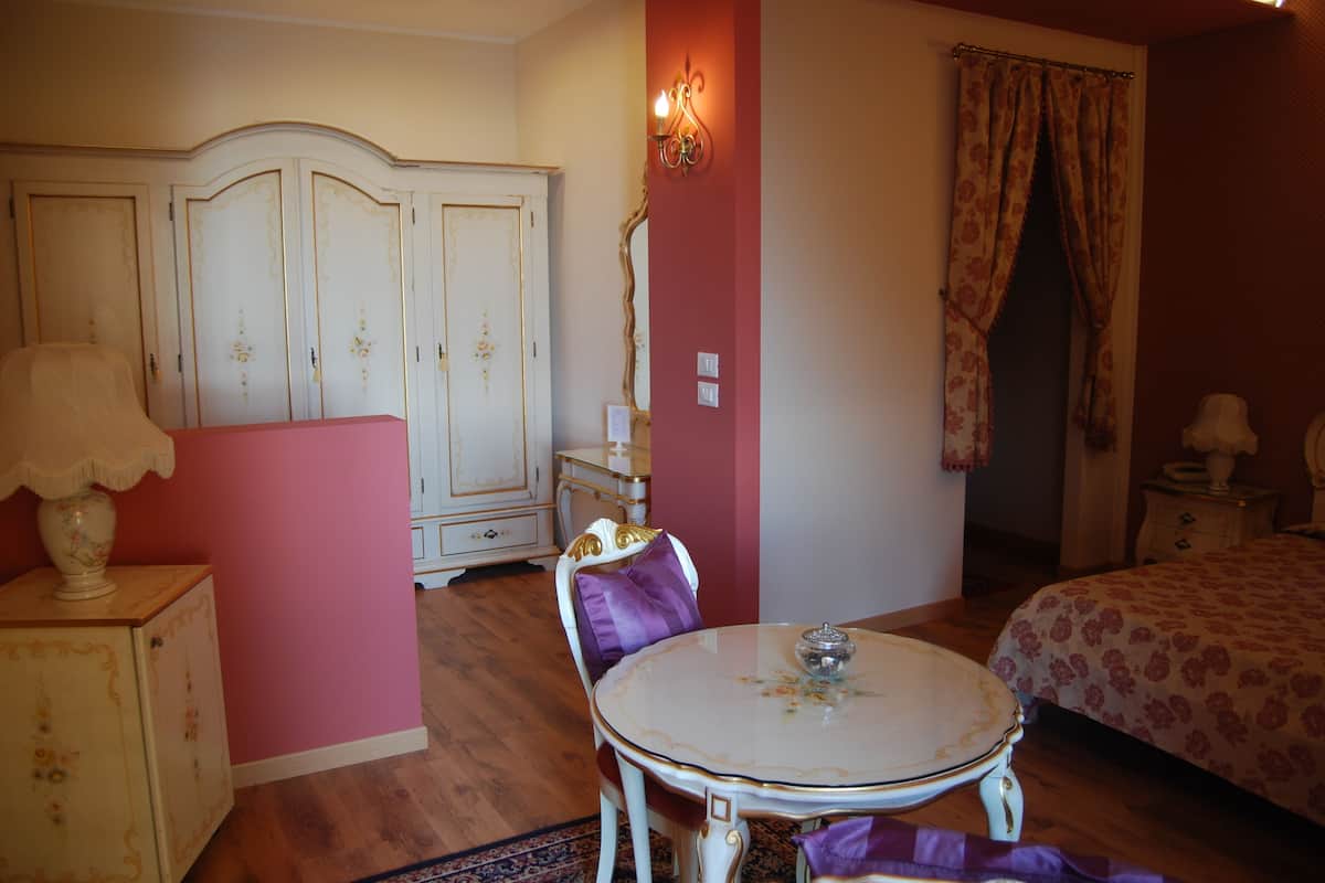 A room with a bed, a round table with a lamp, a wardrobe, and a chair.