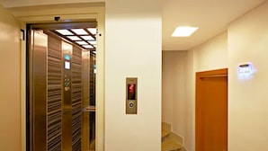 Un ascenseur doté d’un écran numérique, un escalier et une porte avec un éclairage.