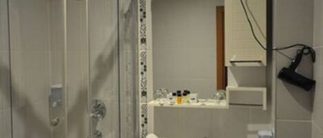 Un baño moderno con ducha envuelta en vidrio, lavamanos blanco y espejo sobre él.