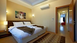 Une chambre d’hôtel avec un grand lit, une table de chevet, une lampe, un climatiseur et un tableau au mur.