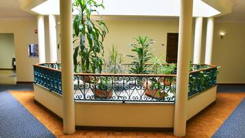 Un balcon abrité, agrémenté de plantes en pot, doté d’un plancher en bois et offrant une vue sur l’espace intérieur.