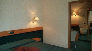 Une chambre d’hôtel avec un lit, une table de chevet, une lampe, une chaise et un miroir.