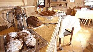 A kitchen with a coffee pot, a cake on a stand, and pastries on a tray. - Hotel Livigno (Livigno)
