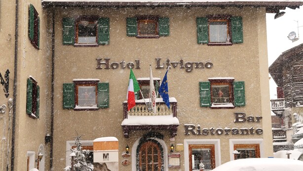 A building with a sign reading "Hotel Livigno Bar Ristorante" and flags above the entrance. - Hotel Livigno (Livigno)