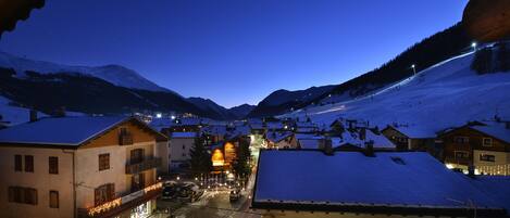A snow-covered mountain town at dusk with illuminated buildings and a clear view of the surrounding landscape.