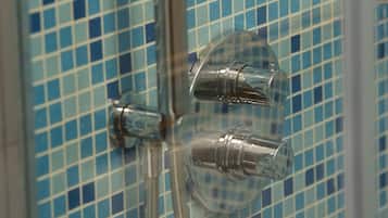 Ducha con pared de azulejos y accesorios cromados.