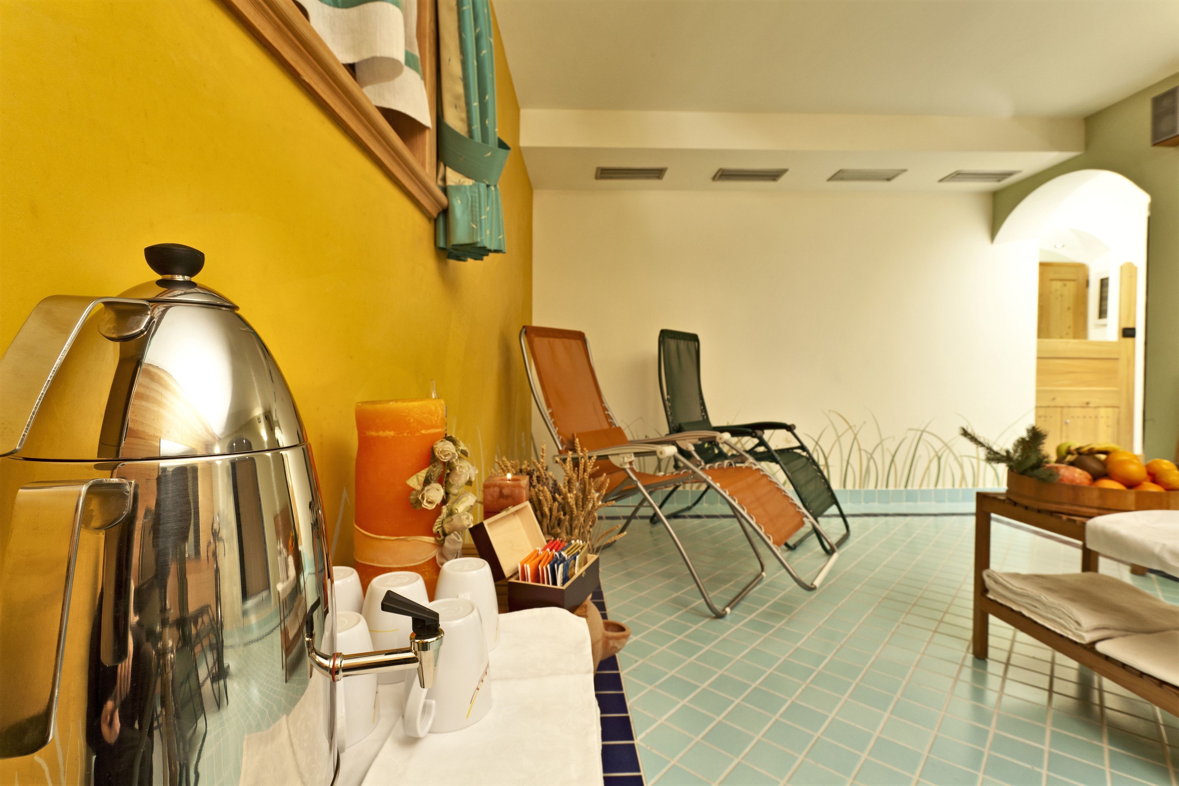A hotel room with a kitchenette, a dining area with a table and chairs, a bed, and a bathroom visible through an archway.