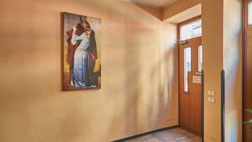Un corridoio con un quadro appeso, una porta in legno e un tappeto rosso.