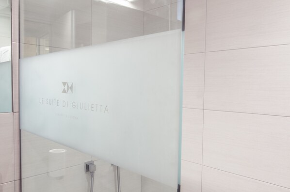A modern bathroom with a frosted glass partition displaying the text "LE SUITE DI GIULIETTA LUXURY IN VERONA." - Le Suite Di Giulietta (Verona)
