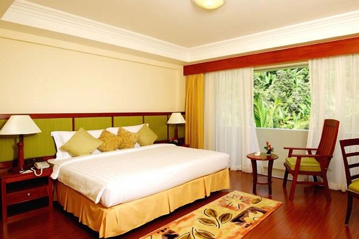 Une chambre d’hôtel avec un lit, une télévision, un bureau et une fenêtre avec des rideaux.