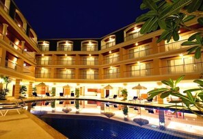 A multi-story hotel with a central pool area, multiple balconies, and indoor plants. - Kalim Resort (Patong)