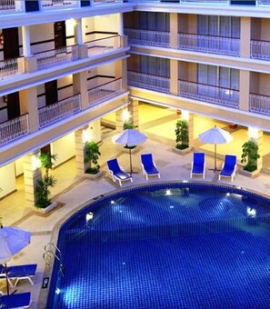 Una piscina al aire libre, sombrillas, sillones reclinables de piscina