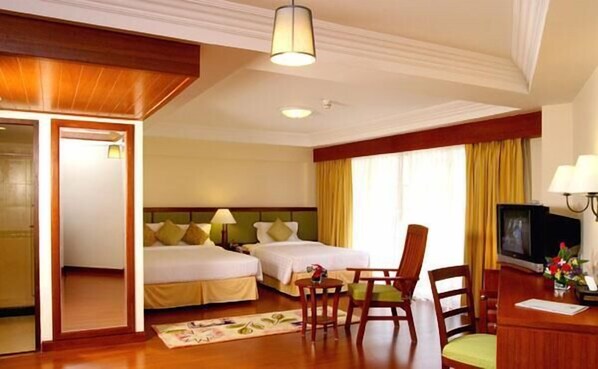A hotel room with two beds, a desk, a chair, a television, and a window with curtains. - Kalim Resort (Patong)