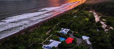 Zona costera con playa, palmeras y varios edificios con paneles solares.