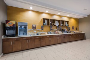 Una larga barra con dispensador de bebidas, refrigerador y diversos alimentos a la vista.