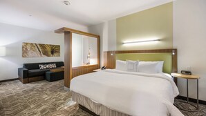 Une chambre d’hôtel avec un grand lit, un canapé, une petite table et un miroir.