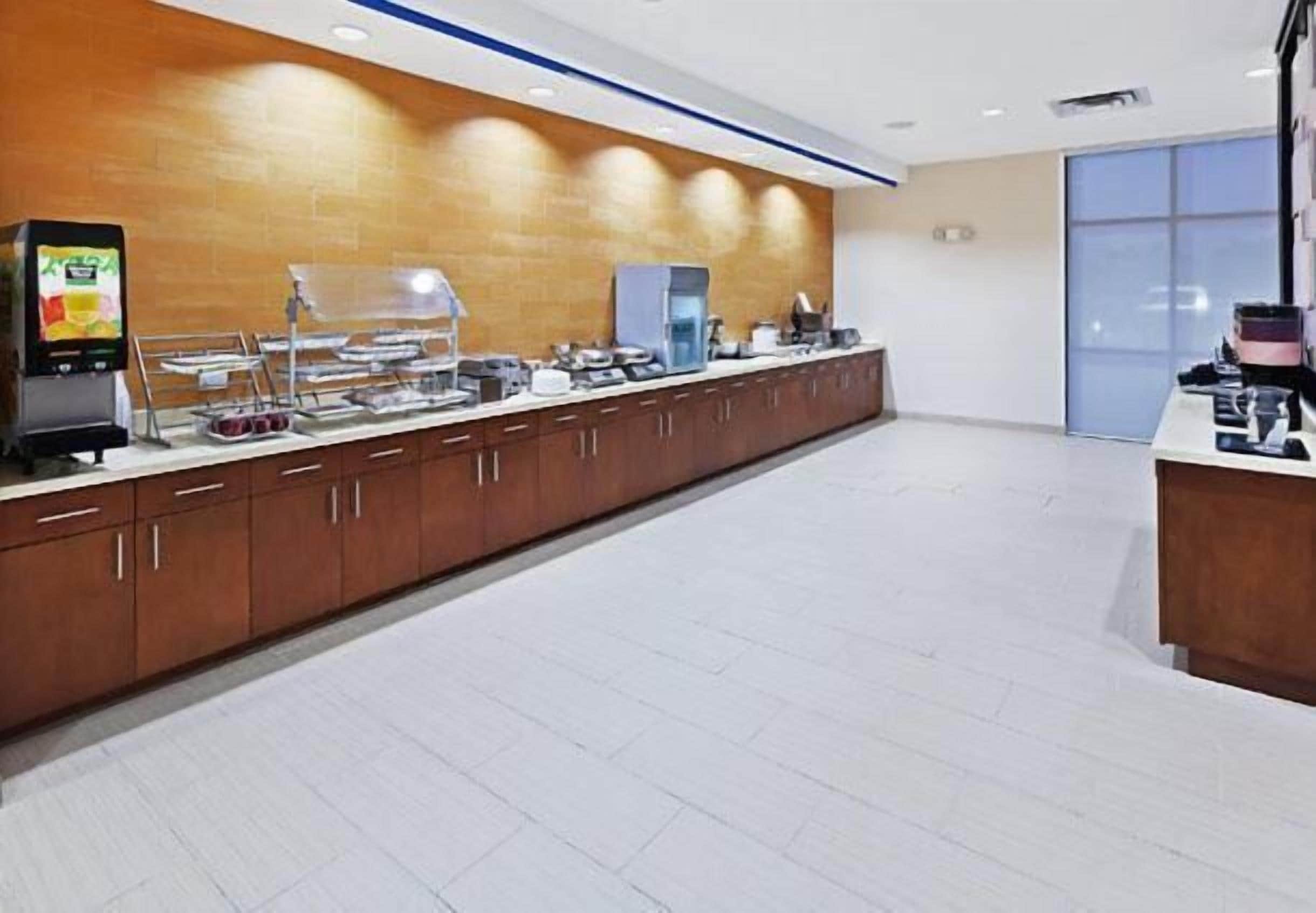 A modern hotel room with a long counter, a coffee machine, and a refrigerator.