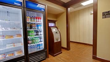 Un hall d’hôtel doté de deux vitrines réfrigérées, d’un distributeur automatique de billets et d’un sol carrelé.
