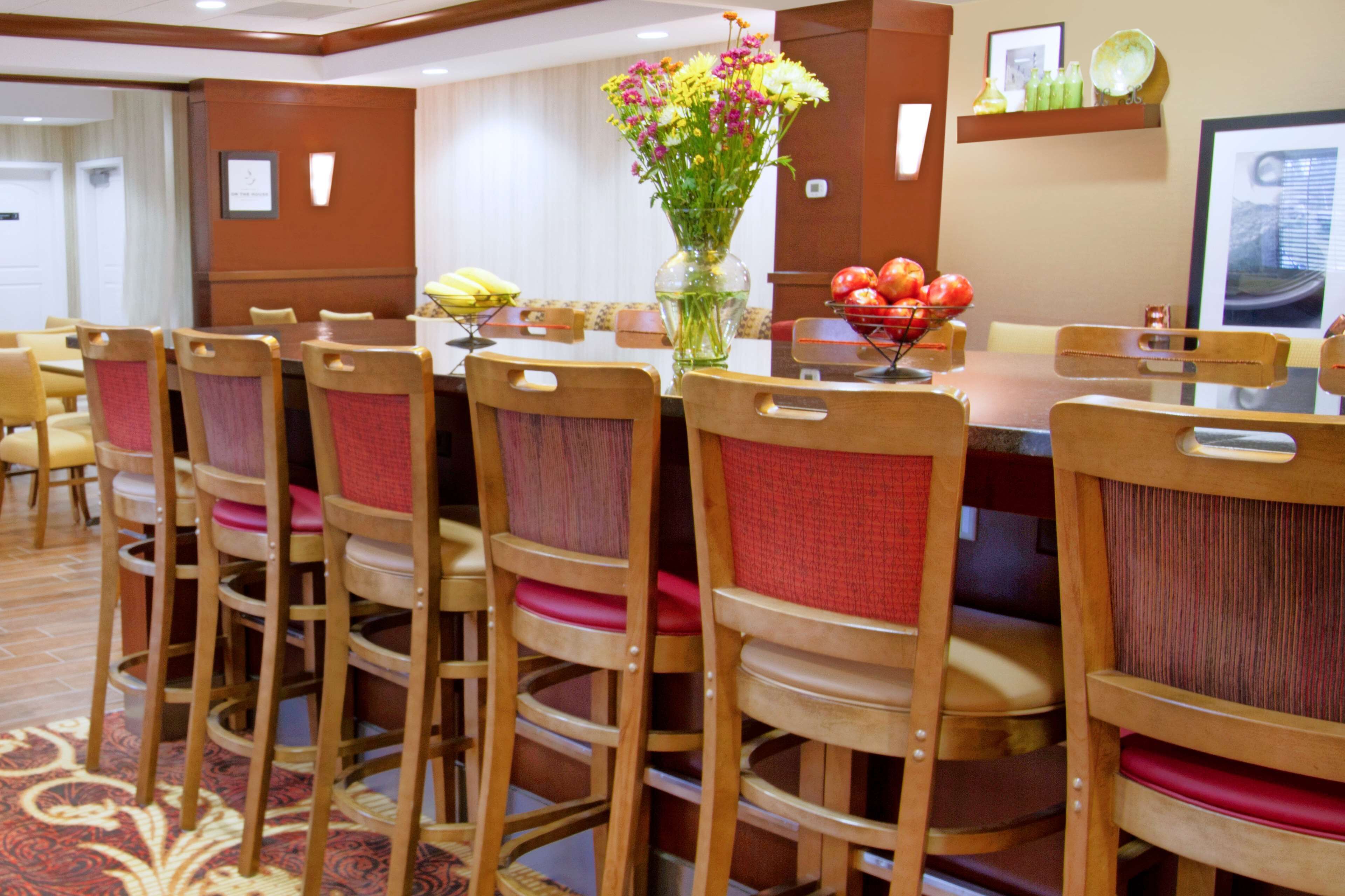 Ein Hotel-Speisesaal mit einem langen Tisch, mehreren Stühlen und einer Blumenvase.