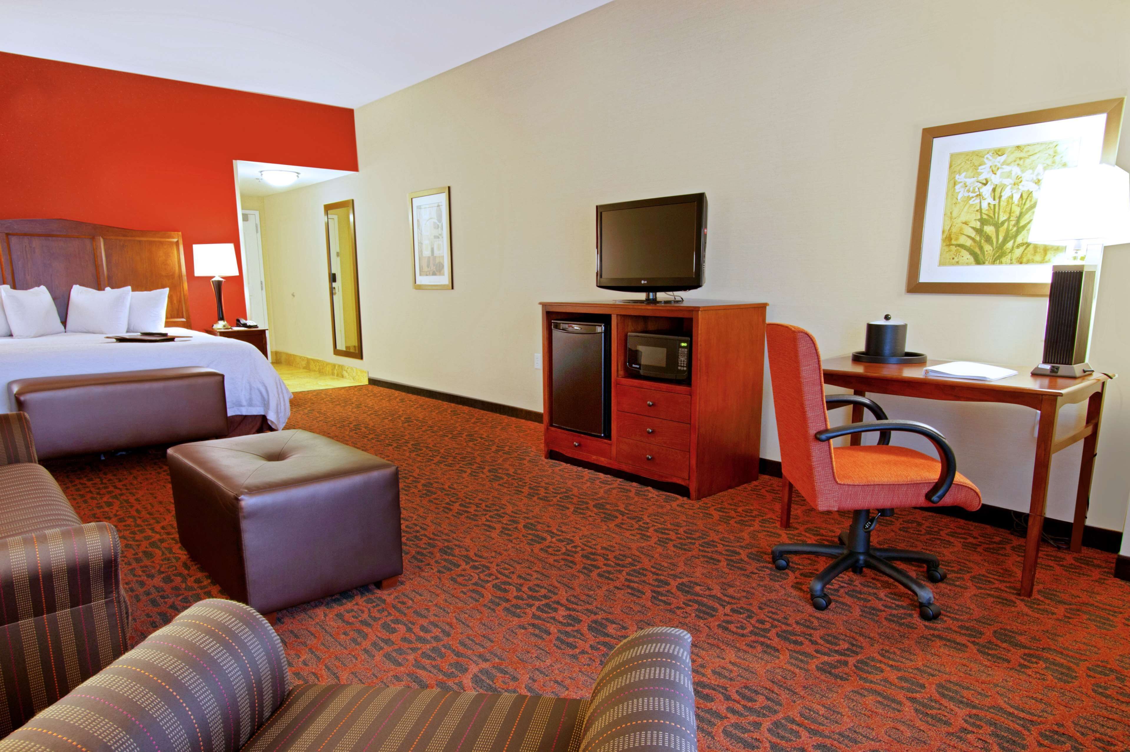 A hotel room with a bed, a desk, a television, and a chair.