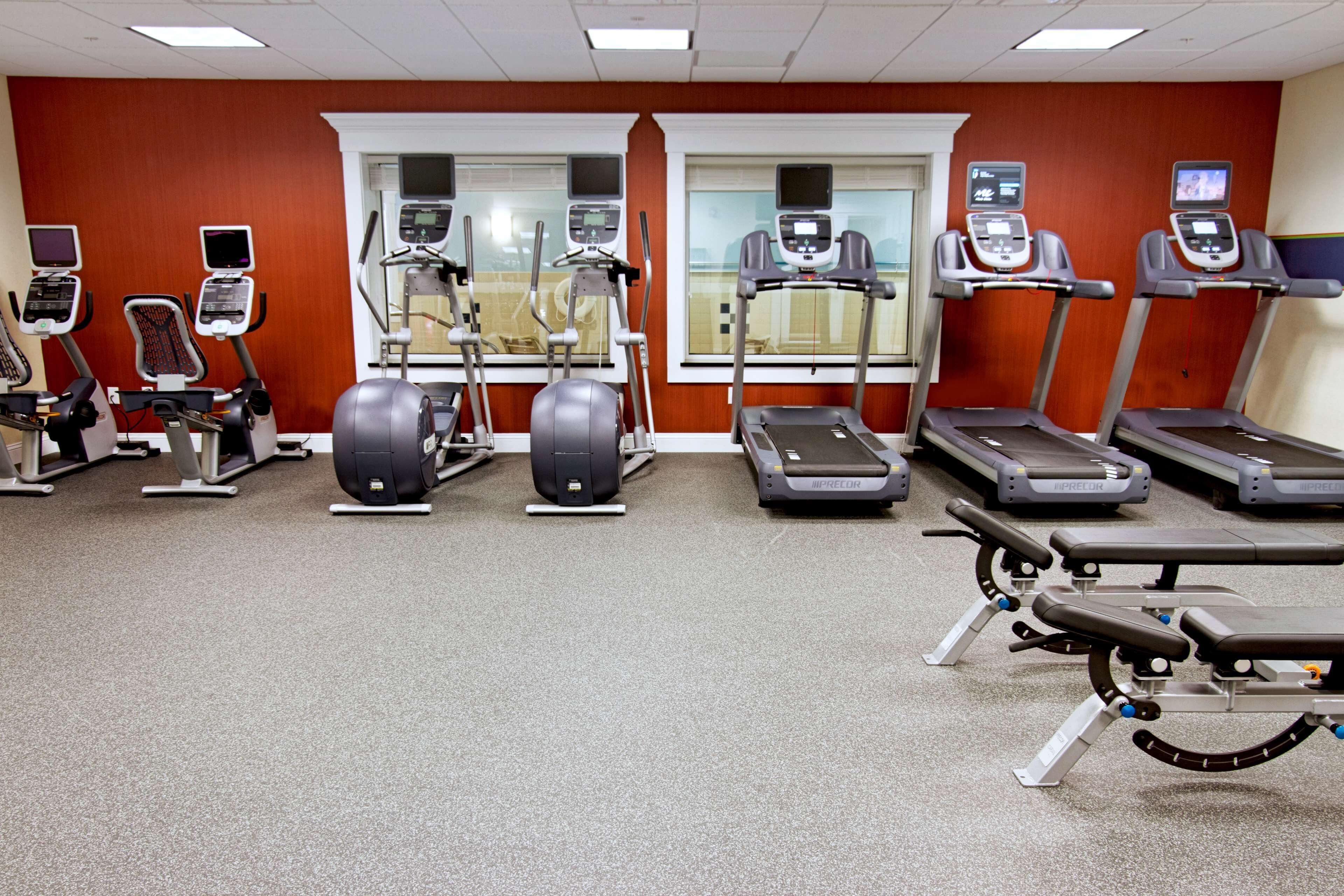 Ein Fitnessstudio mit unterschiedlichen Trainingsgeräten, darunter Laufbänder, Crosstrainer und Ergometer.