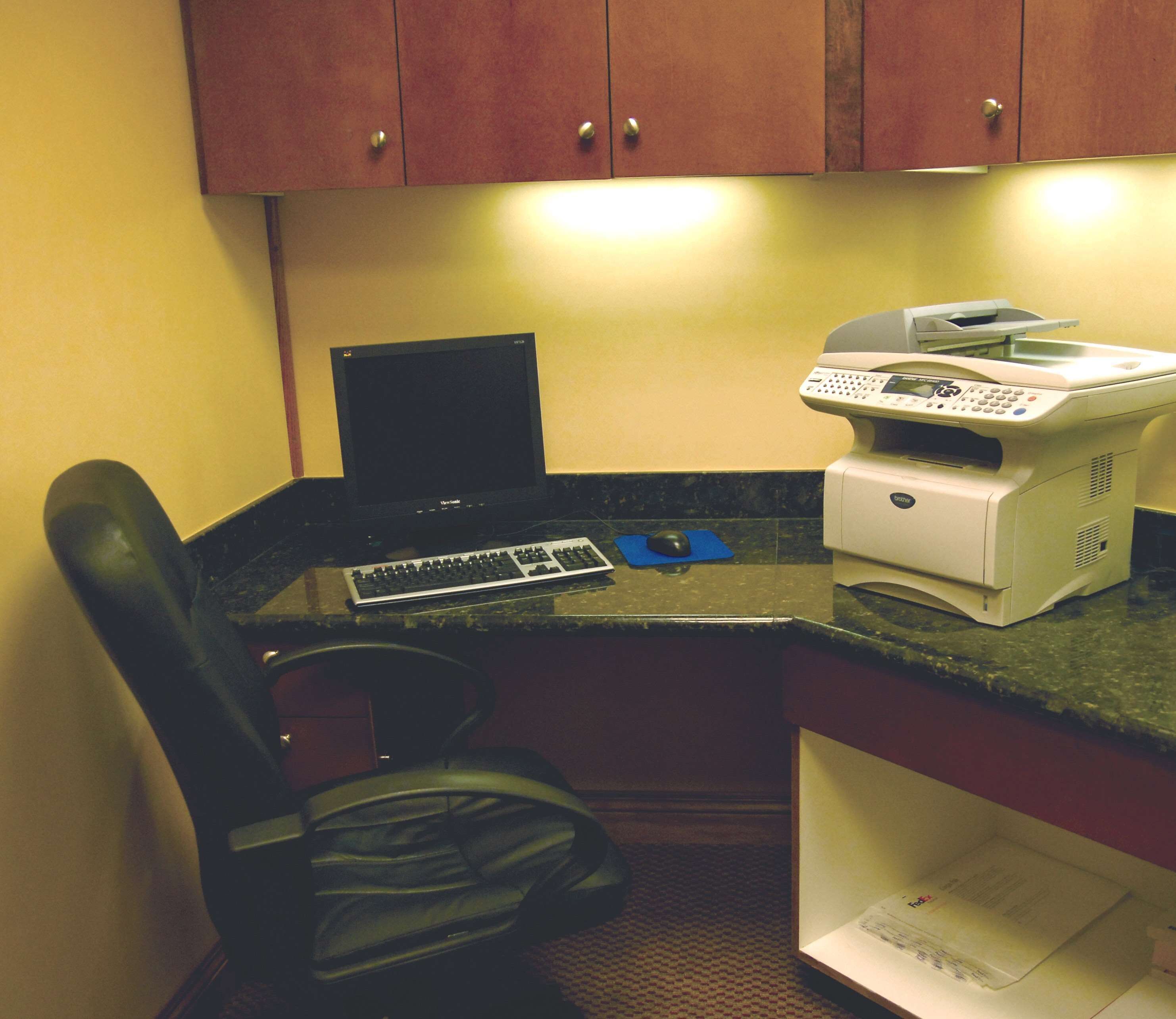 A small office space with a desk, a computer, a printer, and a chair.